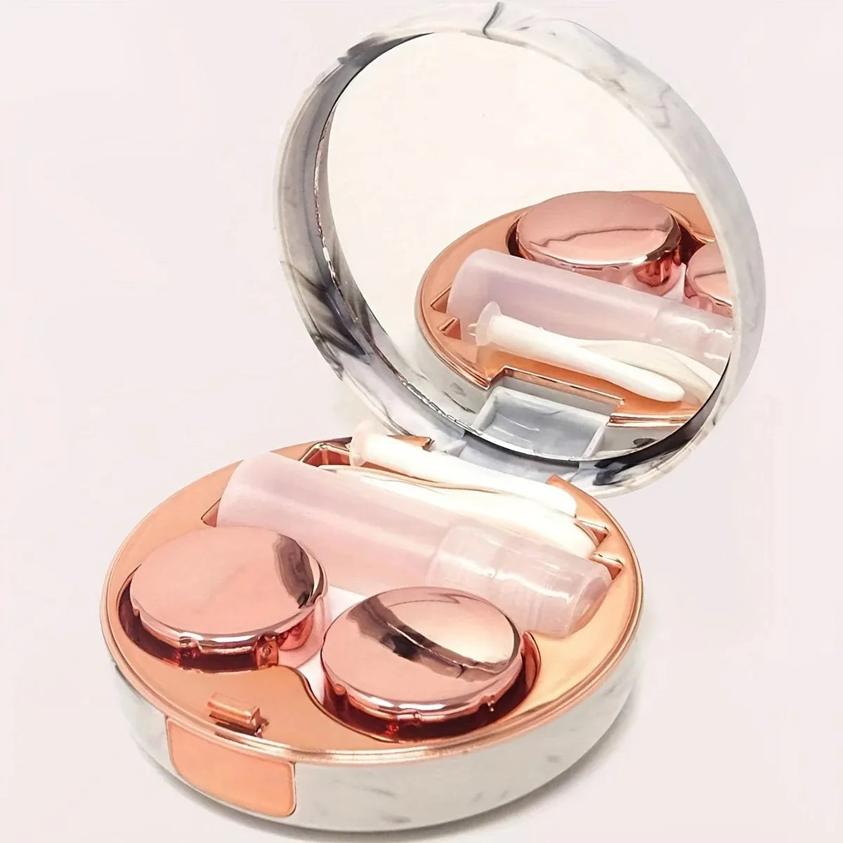 Estuche de mármol color rose gold abierto con espejo, contenedor de lentes y recipiente para solución